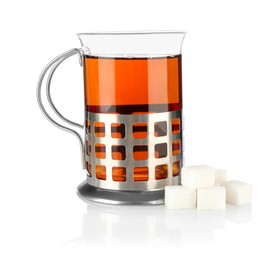 Glass of aromatic tea in holder and sugar cubes isolated on white