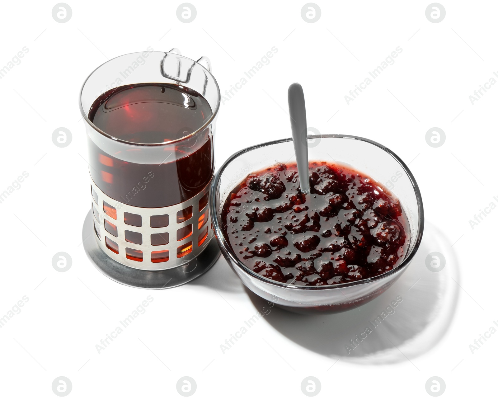 Photo of Glass of aromatic tea in holder and jam isolated on white