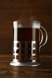 Glass of aromatic tea in holder on wooden table