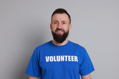 Photo of Positive man wearing t-shirt with word Volunteer on light grey background