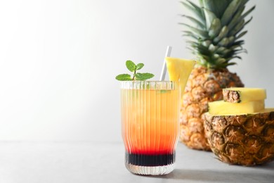 Photo of Tasty pineapple cocktail with mint in glass served on light table, space for text