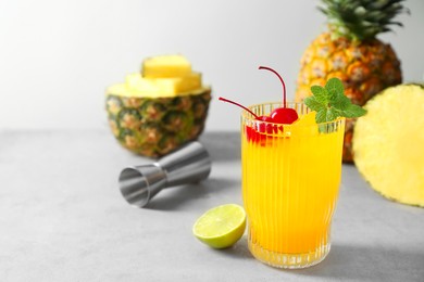 Photo of Tasty pineapple cocktail with mint and cherry in glass served on light table