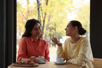 Photo of Happy women with coffee drinks chatting in cafe