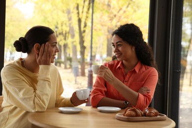 Photo of Happy women with coffee drinks chatting in cafe