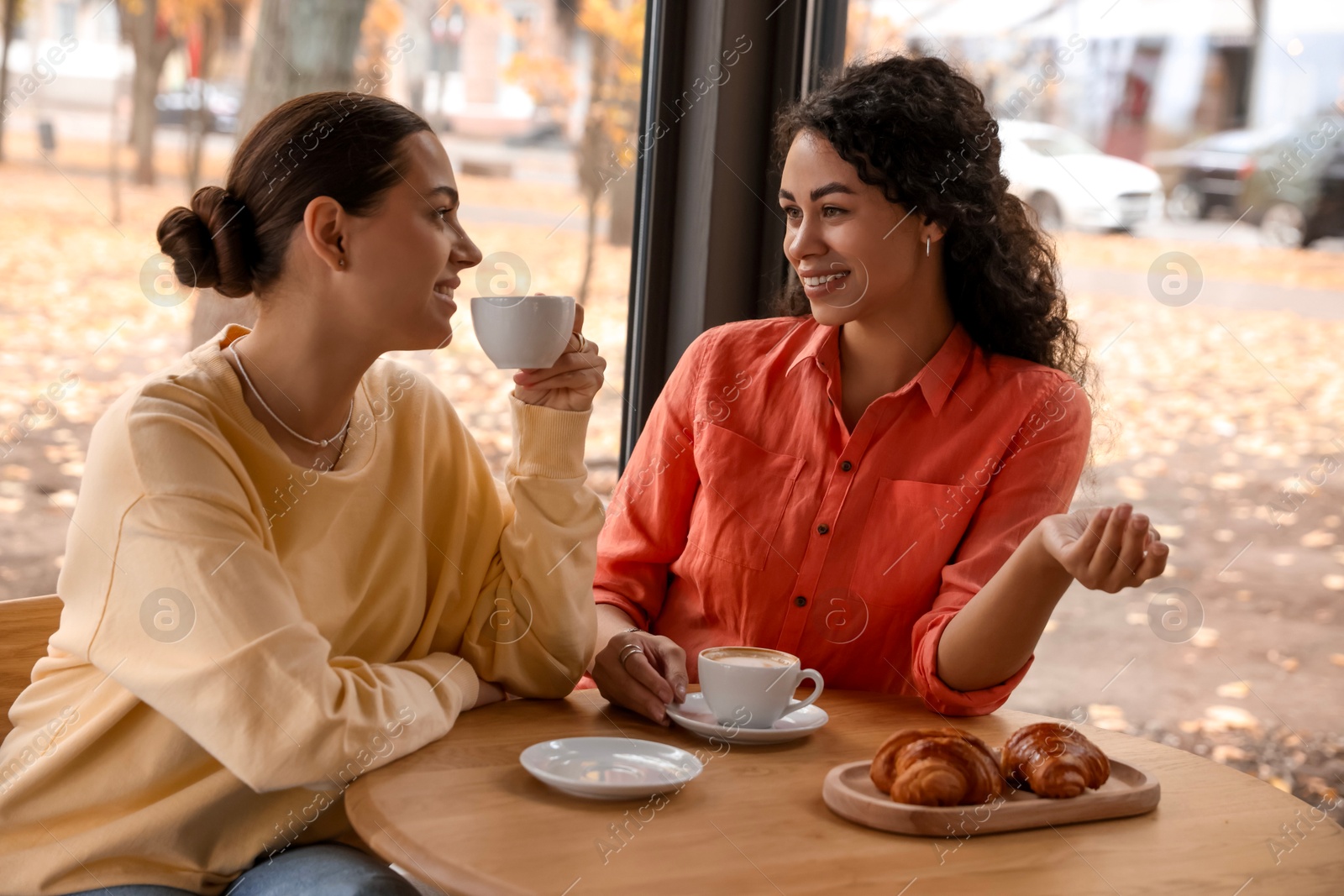 Photo of Happy women with coffee drinks chatting in cafe