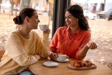 Photo of Happy women with coffee drinks chatting in cafe