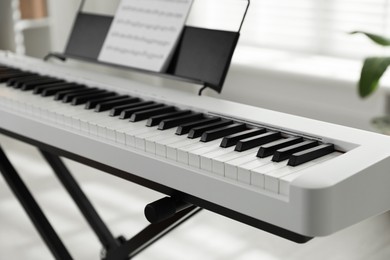 Photo of Synthesizer with music sheet at home, closeup