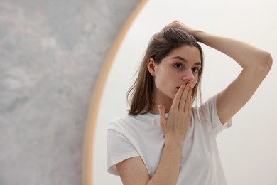 Photo of Girl with hair loss problem near mirror in bathroom, space for text