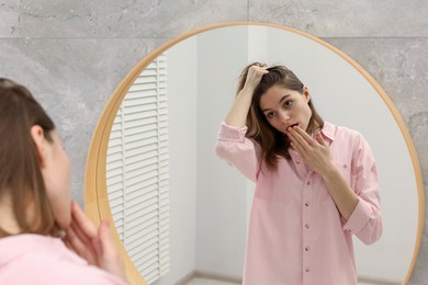 Photo of Girl with hair loss problem near mirror in bathroom