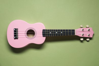 Photo of One ukulele on light olive background, top view