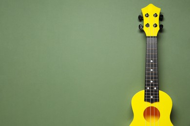 One ukulele on olive background, top view. Space for text