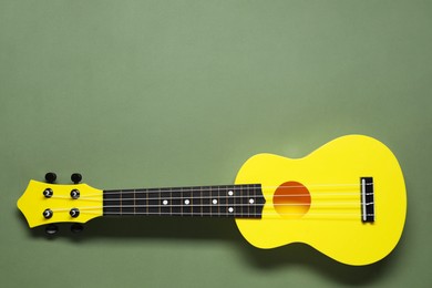 Photo of One ukulele on olive background, top view. Space for text