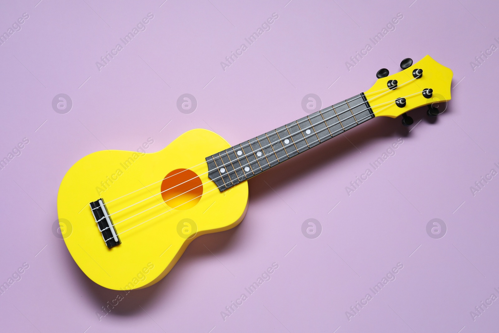 Photo of One ukulele on violet background, top view