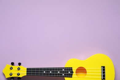 Photo of One ukulele on violet background, top view. Space for text