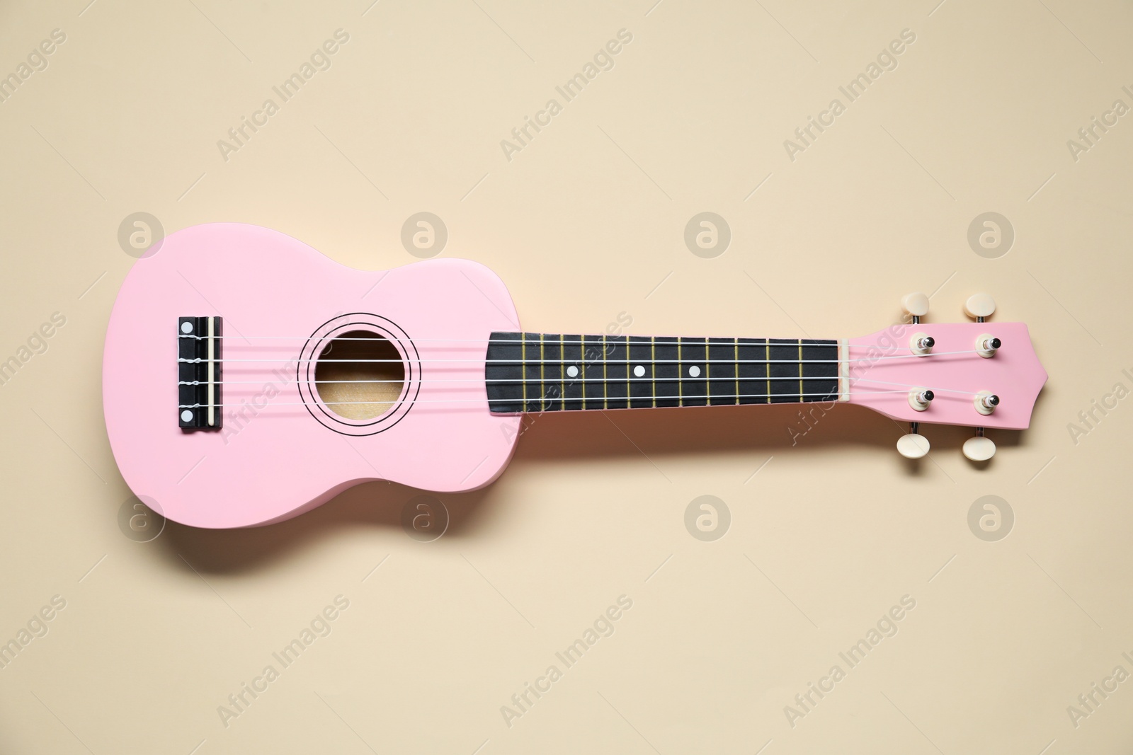 Photo of One ukulele on beige background, top view