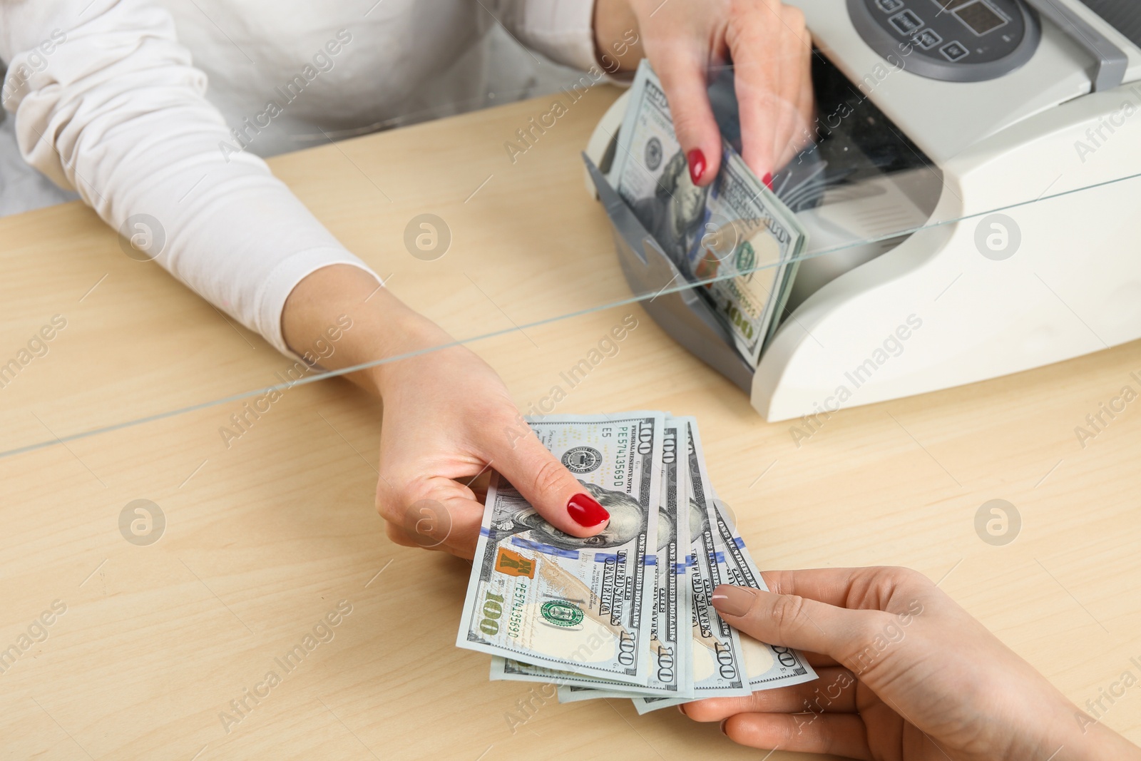 Photo of Cashier giving dollar banknotes to client at table in money exchange, closeup