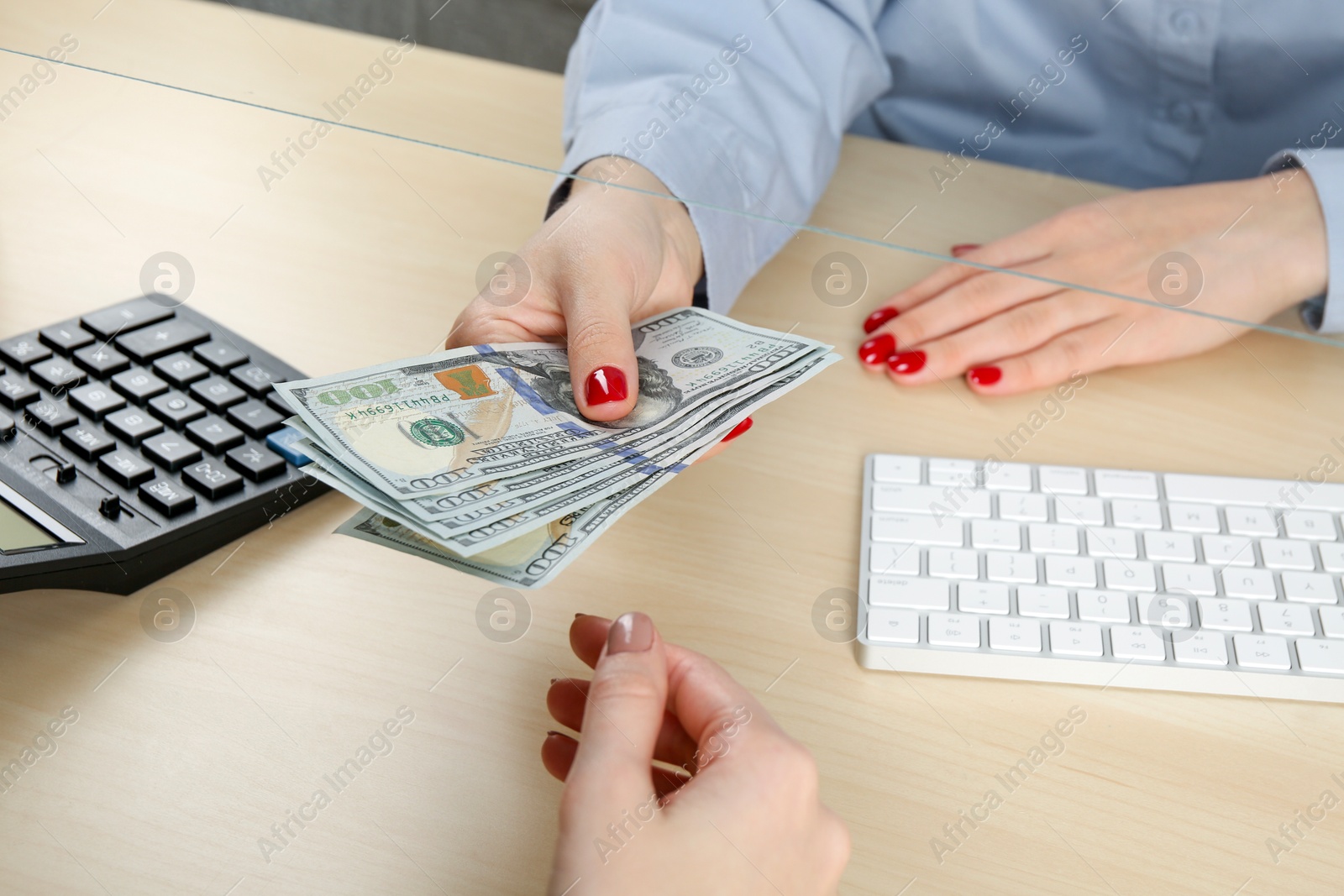 Photo of Cashier giving dollar banknotes to client at table in money exchange, closeup