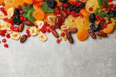 Photo of Mix of different dried fruits on gray textured table, top view. Space for text