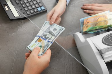 Photo of Cashier giving dollar banknotes to client at table in money exchange, closeup