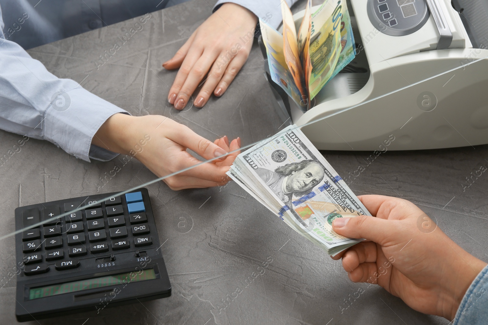 Photo of Cashier giving dollar banknotes to client at table in money exchange, closeup