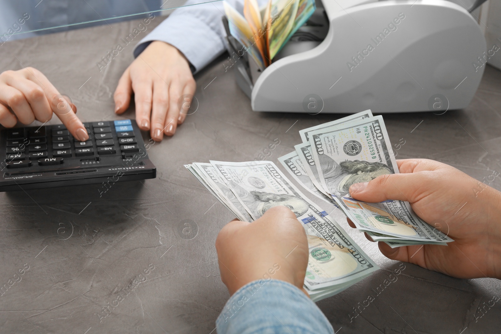 Photo of Client counting money at table in currency exchange, closeup