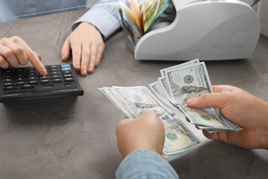 Photo of Client counting money at table in currency exchange, closeup