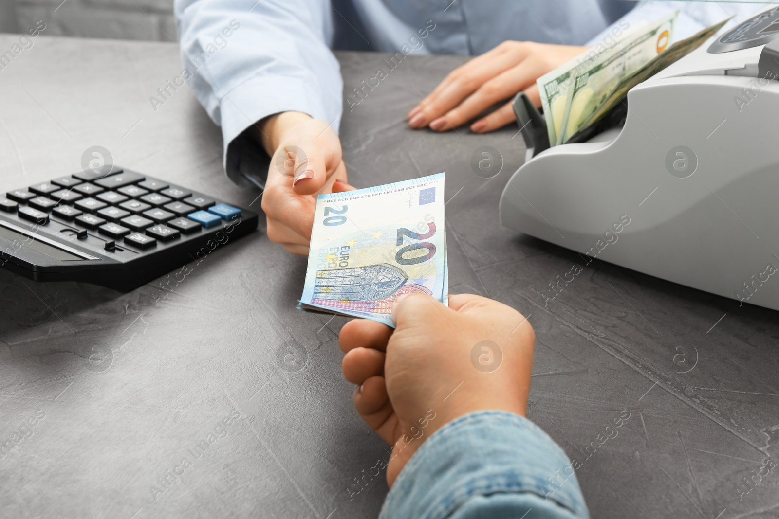 Photo of Client giving euro banknotes to cashier at table in money exchange, closeup