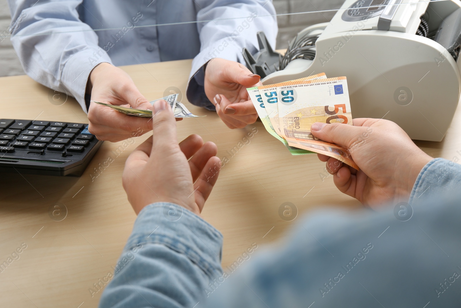 Photo of Client exchanging money at wooden table, closeup