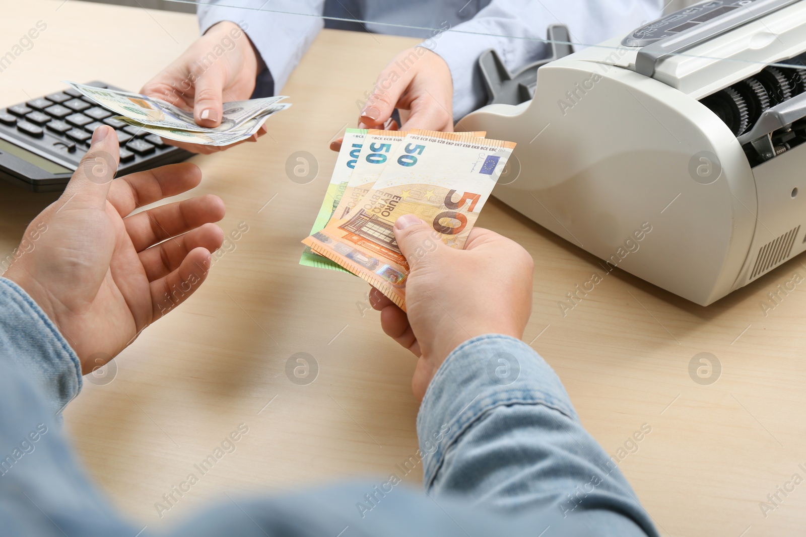 Photo of Client exchanging money at wooden table, closeup