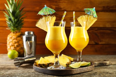 Photo of Tasty pineapple cocktail in glasses served on wooden table