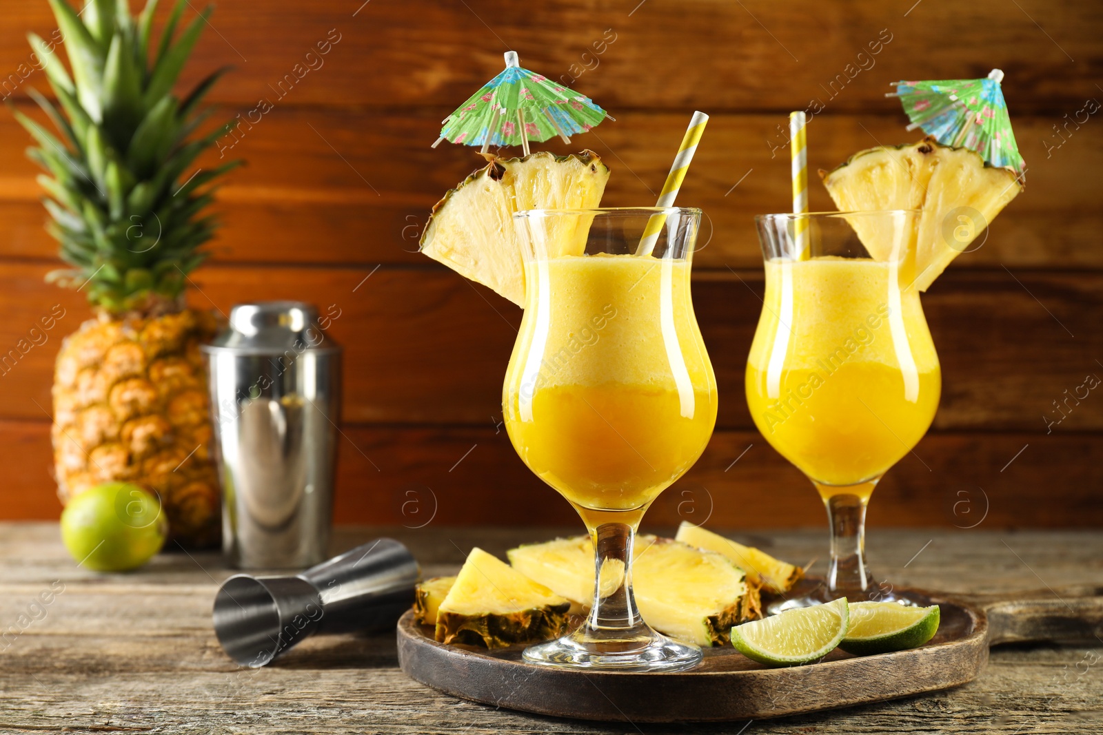 Photo of Tasty pineapple cocktail in glasses served on wooden table