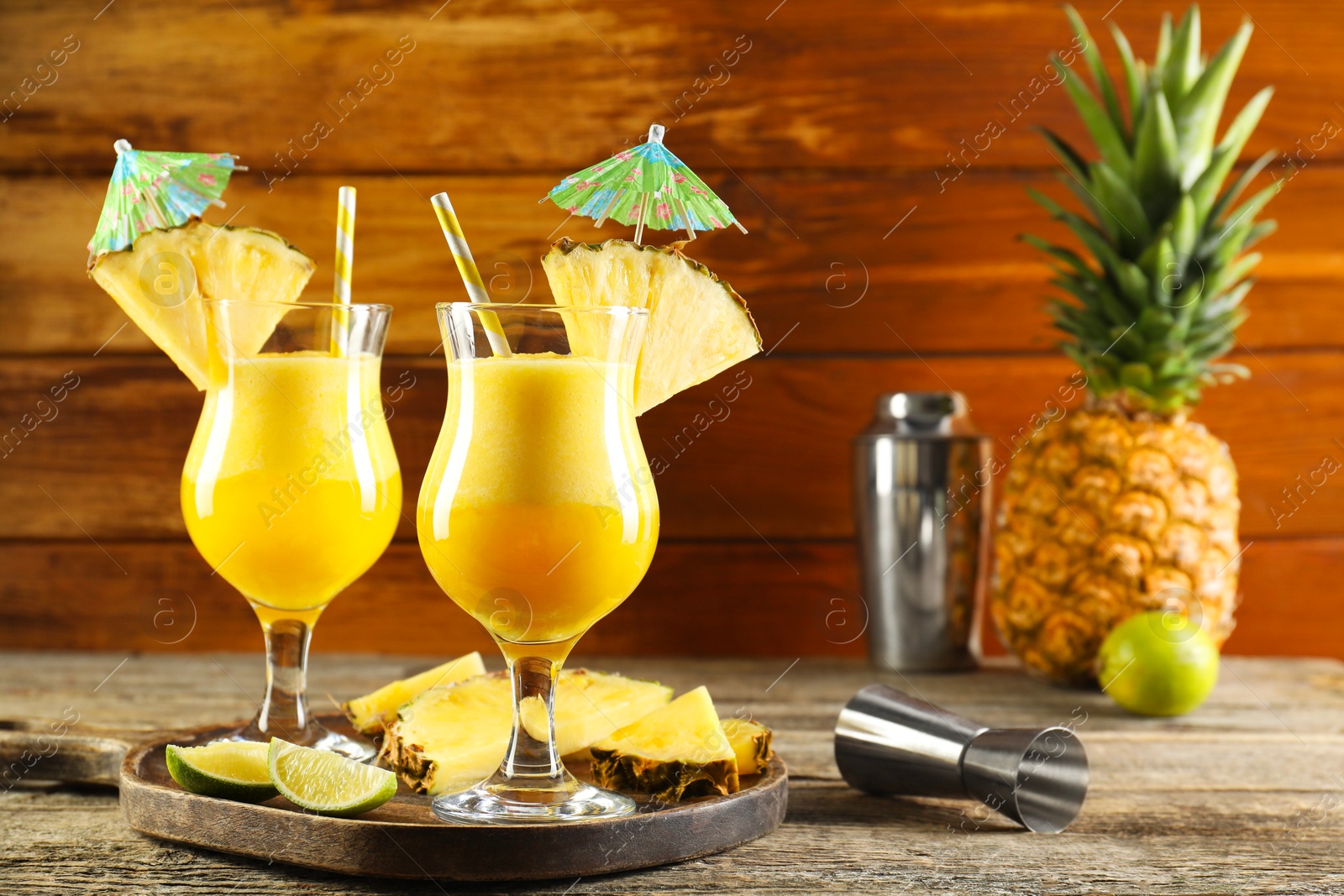 Photo of Tasty pineapple cocktail in glasses served on wooden table