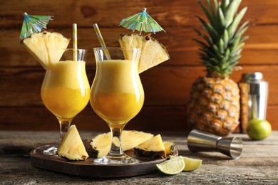 Photo of Tasty pineapple cocktail in glasses served on wooden table