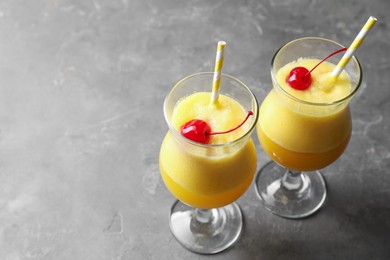 Photo of Tasty pineapple cocktail in glasses served on grey table, space for text