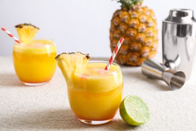 Photo of Tasty pineapple cocktail in glasses served on white table