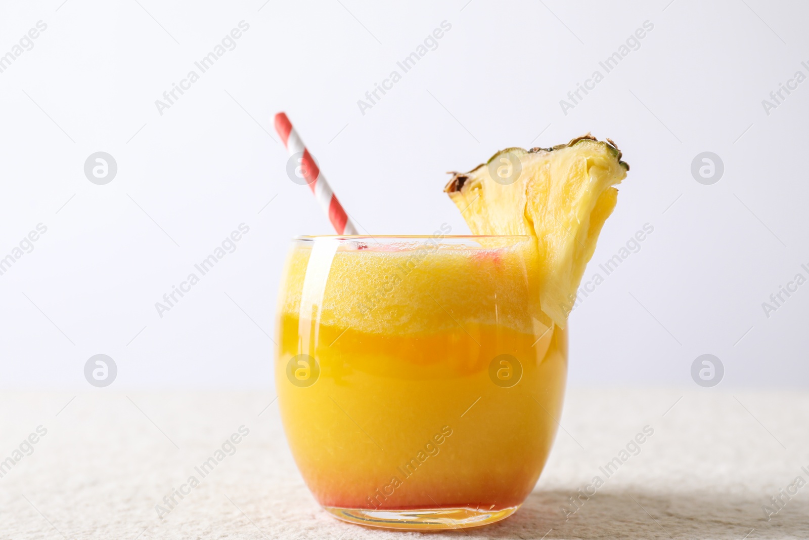 Photo of Tasty pineapple cocktail in glass served on white table