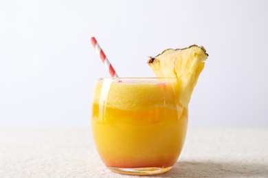 Photo of Tasty pineapple cocktail in glass served on white table