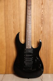 Photo of One modern electric guitar near wooden wall