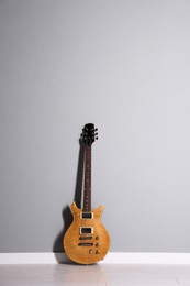 Photo of One modern electric guitar near light grey wall. Space for text