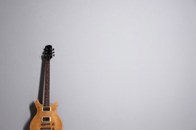 Photo of One modern electric guitar on light grey background. Space for text