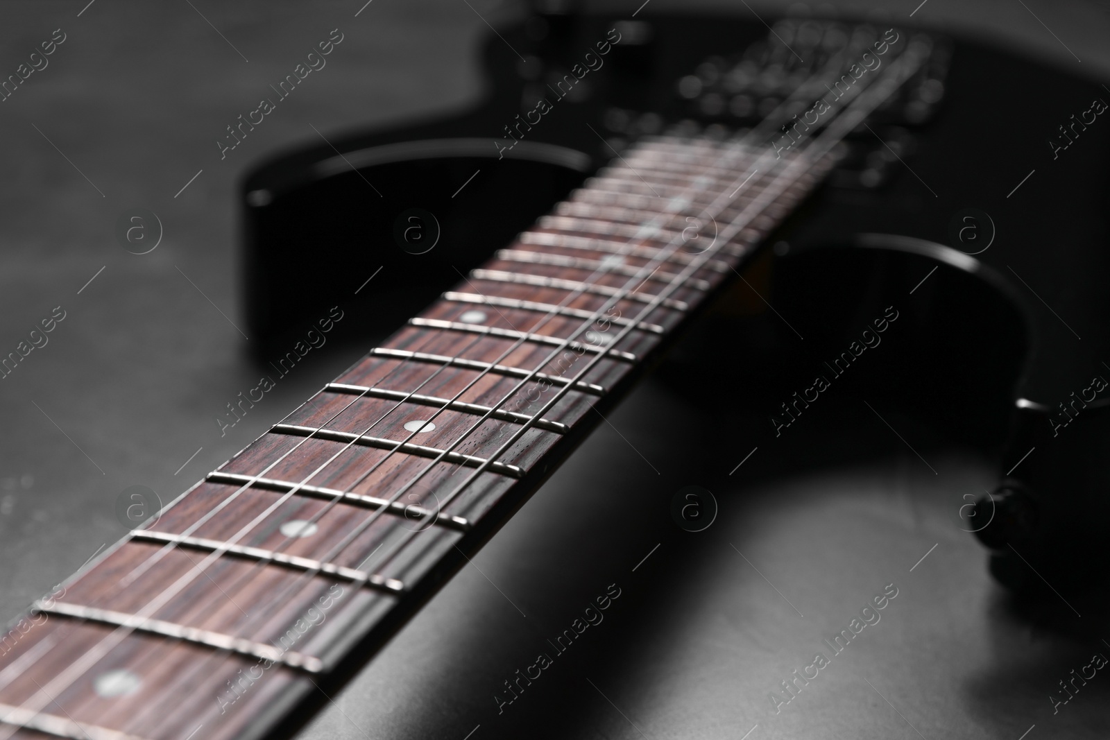 Photo of Modern electric guitar on black background, closeup