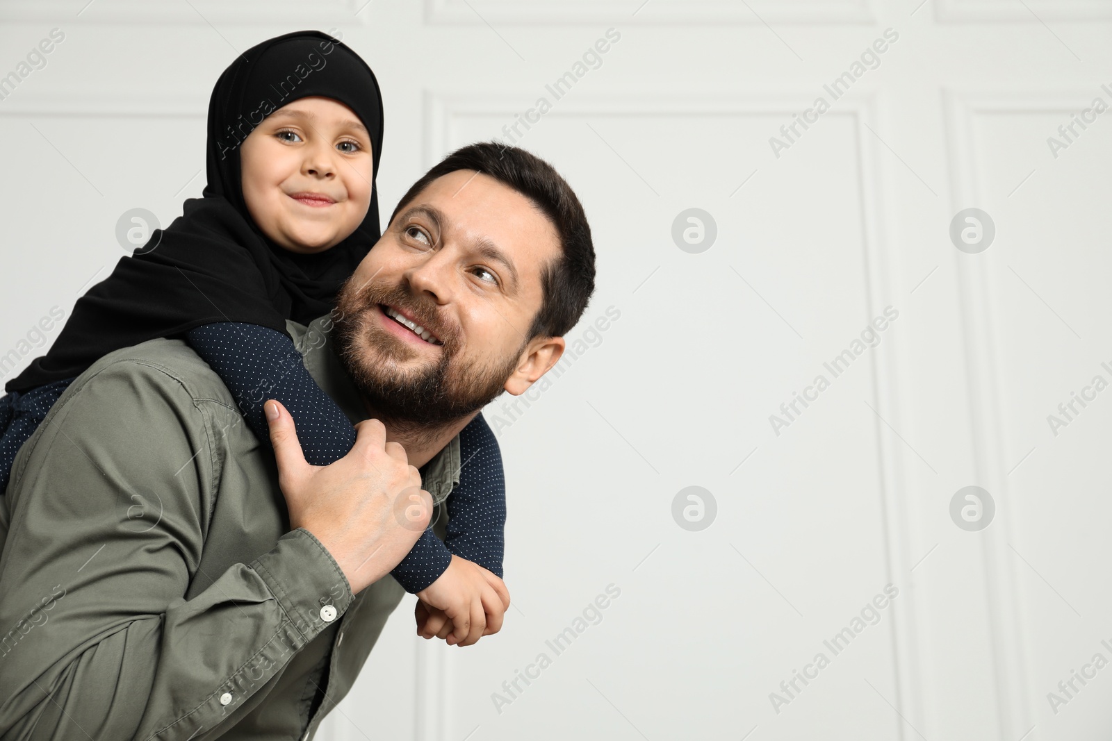 Photo of Muslim man and his daughter spending time together at home, space for text