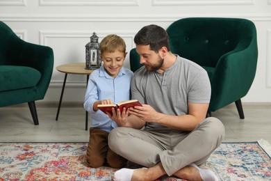 Muslim man and his son reading Quran at home