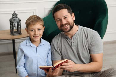 Photo of Muslim man and his son reading Quran at home