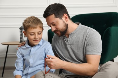 Photo of Muslim man and his son with prayer beads at home