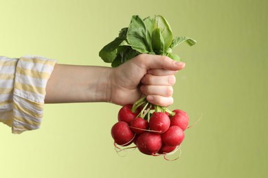 Photo of Woman with bunch of fresh radishes on green background, closeup