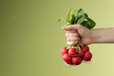 Photo of Woman with bunch of fresh radishes on green background, closeup. Space for text