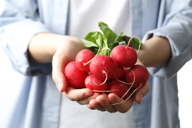Photo of Woman with bunch of fresh radishes on white background, closeup