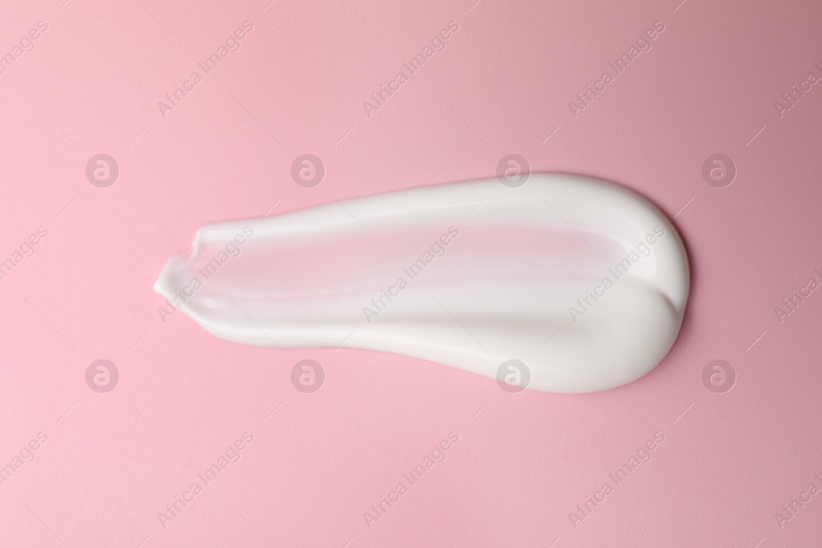 Photo of Cream on pink background, top view. Sample of cosmetic product