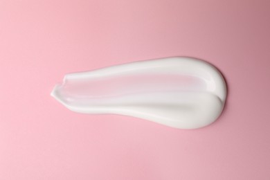 Photo of Cream on pink background, top view. Sample of cosmetic product